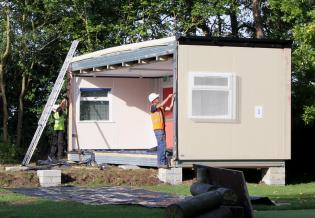 The first section of the new classroom is in position, and the builders prepare the edges for the next section to be lifted alongside
