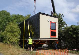 The builders fit the crane's lifting straps around the classroom unit