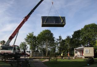 The crane has to lift the classroom unit high enough to clear the trees