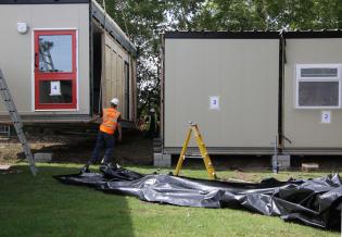 The builders guide the fourth classroom section into position